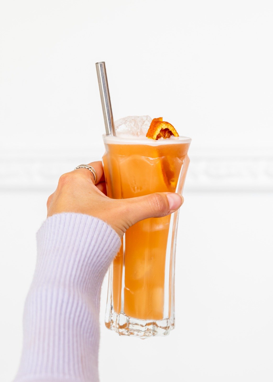 Hand holding tall orange cocktail