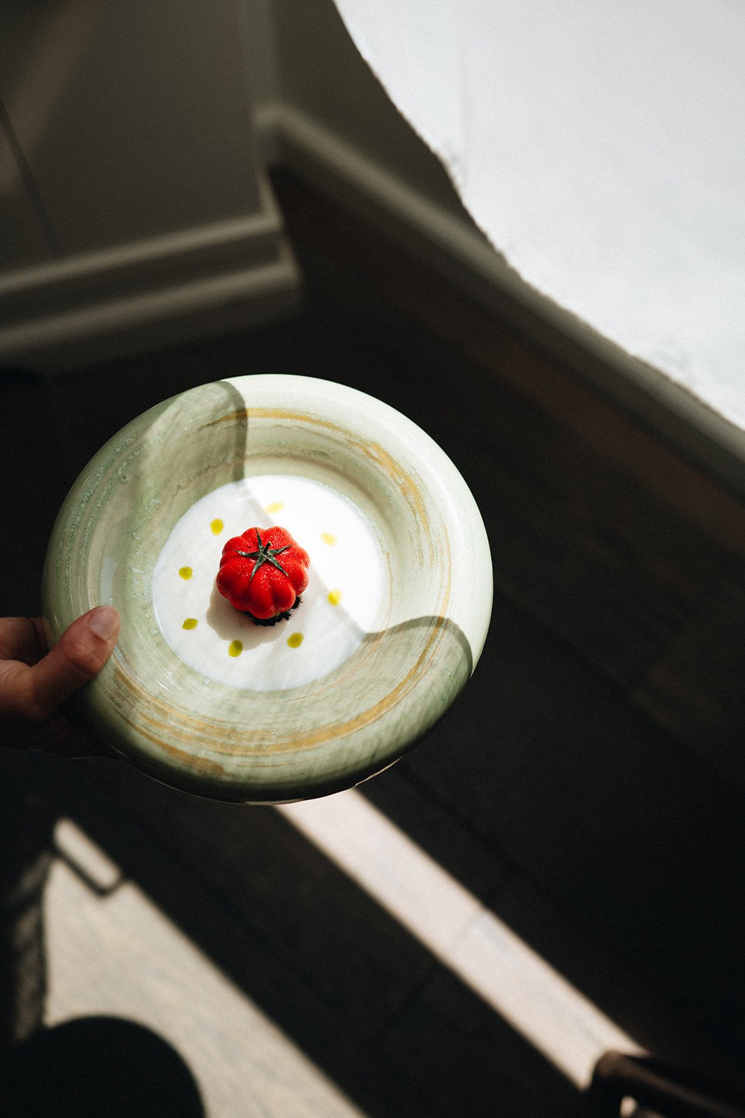 Hand holding green plate with tomato